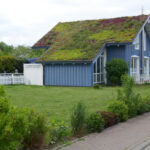 Idyllic blue wooden house in the countryside with green plants on the roof. Hohwacht, Schleswig-Holstein, Germany
